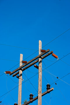 Electrical power lines, posts and infrastructure of the electricity grid against a blue sky.