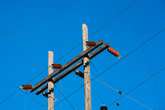 Electrical power lines, posts and infrastructure of the electricity grid against a blue sky.