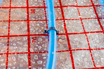 Installing plastic pipes for underfloor heating system on insulated mat