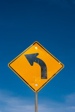 Turn Left arrow symbol on a yellow metal street sign.