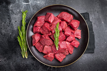 Diced Raw Boar meat, fresh Game Meat in a plate. black background. top view