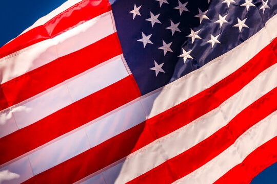 A large stars and stripes flag, the American flag fluttering in the breeze, in a blue sky.