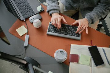 Caucasian middle aged man working at desk using wireless keyboard with laptop, smartphone, coffee...