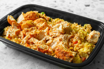 A view of a meal prep container of chicken and fried rice.