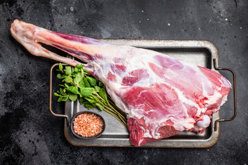 Uncooked whole mutton leg, raw organic lamb meat. black background. top view