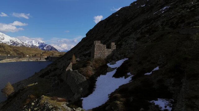 Historic ruined towers on snowy mountainside, Italian Alps, Italy. Aerial drone orbiting, lateral view