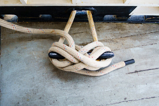 A rope fastened around a metal horn cleat on a ship's desk, secure mooring rope, close up.