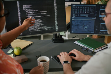 Caucasian middle aged man and Black woman collaborating at workstation, analyzing code on computer...