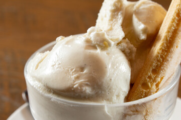 A closeup view of vanilla ice cream scoops and a ladyfinger.