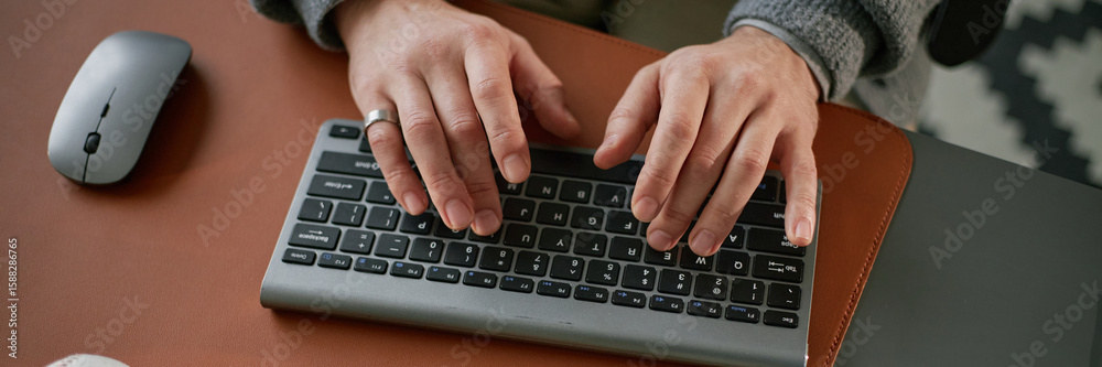 Fototapete Website header shot of Caucasian middle aged man typing on wireless keyboard with both hands, wearing ring, working at desk with computer mouse nearby, close up of hands and keyboard