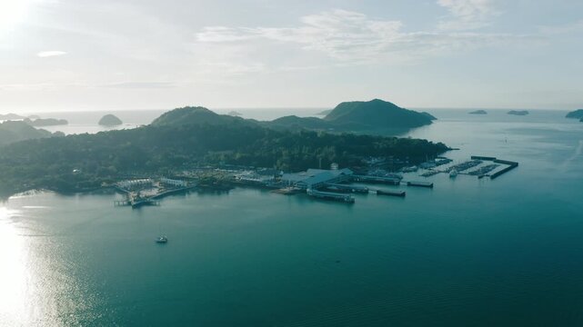 March 11th, 2022 - Langkawi, Malaysia: 4k Establishing b-roll aerial shot of Kuah Jetty terminal complex and marina. High angle view of passenger ferry docks, yachts parked at the harbor, and lush gre