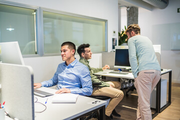 Obraz premium Office workers using desktop computer and collaborating on a project in a modern coworking space