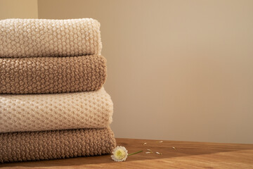 Stack of towels in neutral colors in modern aesthetic interior. Fabric bathroom accessories for hygiene, spa and skin care.
