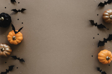 Halloween holiday mockup with party decorations of pumpkins, bats on gold background top view. Happy halloween greeting card in flat lay style.