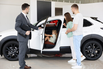 Salesman showing new car to family in salon