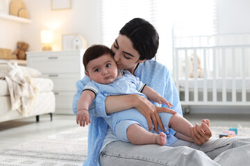 Mother kissing her cute baby at home