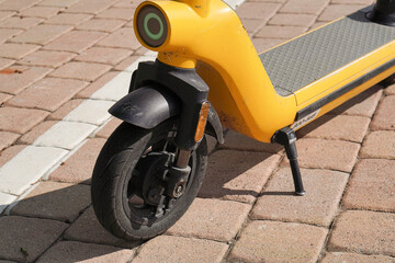 Close-up of yellow electric scooter standing outside on sunny day