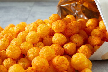 A view of a pile of pizza-flavored cheese balls, spilling out of the bag.