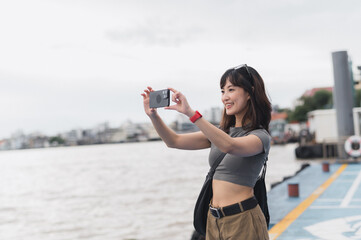 Happy solo southeast asian woman teenager blogger express joy to take photo with smartphone. world...