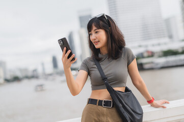 Happy young southeast asian woman teenager blogger world travel explorer using smartphone searching...