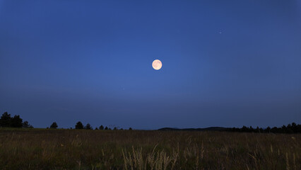 Full Moon with stars, planets and rural countryside silhouettes.