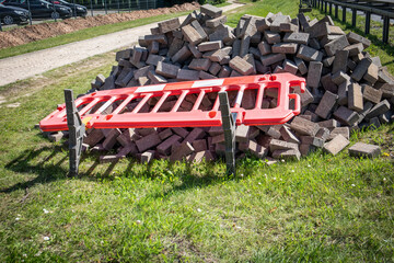 Construction Materials with Fallen Safety Barrier on Grass During Urban Sidewalk Renovation