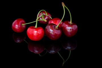 Fresh cherries on a black background with reflection. 