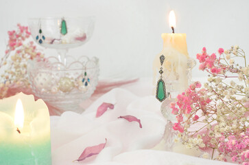 Baroque style table decoration: two burning candles, rose petals, earrings, lot of baby's breath and light tablecloth. Shallow depth of field. 