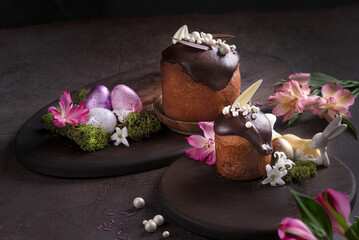 Easter cakes with icing on a dark background among flowers