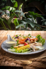 Delicious salad with crusty bread, on a plate on a rustic wooden table in the garden.