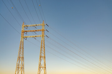 Isolated high voltage electricity pylon with cables. Blue sky on the background.