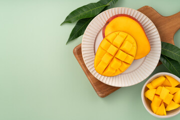 Fresh ripe mango with cubes on green table background.