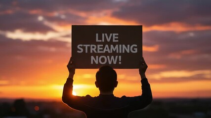 Silhouette of a person holding a sign at sunset promoting a live broadcast event now. LIVE STREAMING NOW