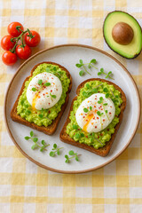 Healthy avocado toast topped with poached eggs, microgreens, and chili flakes on a checkered tablecloth