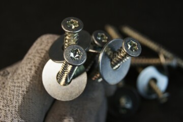 Construction worker holding large bolts with washers. Construction work process.