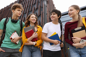 Group of happy teenagers near building outdoors, low angle view