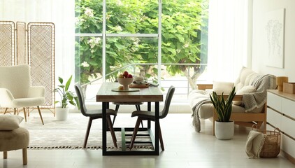 Wooden table, chairs, sofa and decor in dining room. Interior design