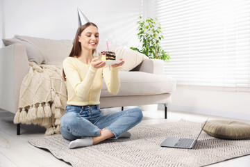 Birthday celebration. Happy woman with piece of cake having video call via laptop at home