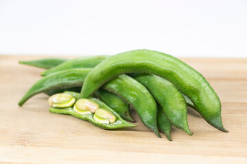 Close up of a wooden crate filled with broad beans, the green bean on background, closeup of broad bean Raw .