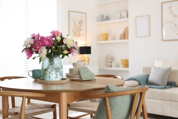 Dining table with beautiful flowers and dishware in room, space for text. Interior design