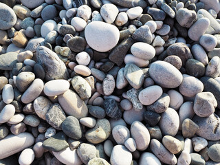 Close-up of a pile of smooth sea pebbles in natural shades of grey, beige, and brown. Stone texture background for spa, nature, relaxation, or coastal design themes.