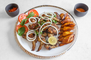 Ailes de poulet avec alloco (banane plantain) et salade de tomates – plat africain traditionnel © Lina Taravella