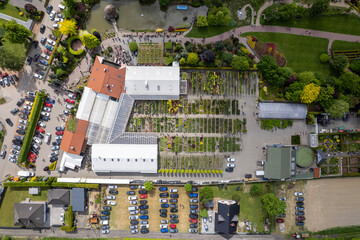 Aerial View of Urban Garden Center with Greenhouses, Plant Rows, Pond, and Visitor Pathways
