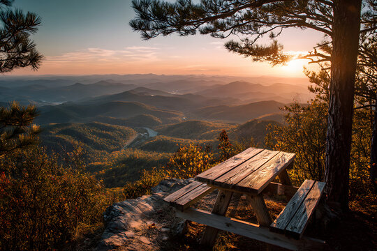 Serene Sunset Picnic: A breathtaking panorama unfolds as a wooden picnic table overlooks a vast mountain range at sunset, promising tranquility and an idyllic escape.