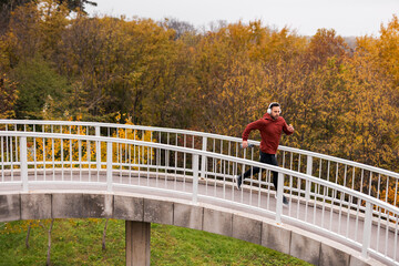 Man Runs on Outdoor Overpass Amid Autumn Trees