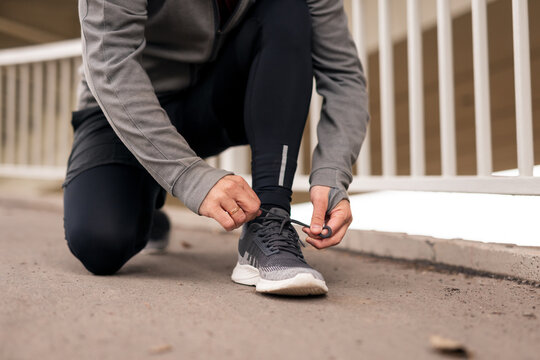 Person Tying Sports Shoe Laces During Outdoor Fitness Exercise Session