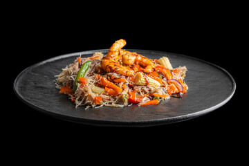 A colorful serving of stir-fried rice noodles with shrimp and mixed vegetables is presented on a black plate against a dark background, showcasing vibrant textures and Asian-inspired flavors