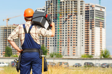 Man builder. Handyman with a tool belt. Male builder. Construction worker holding a tool box....