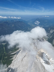 Drone view of the Zugspitze summit, Germany’s highest peak in the Bavarian Alps. The aerial photo captures the mountain station, observation platforms, rugged cliffs, and the breathtaking alpine