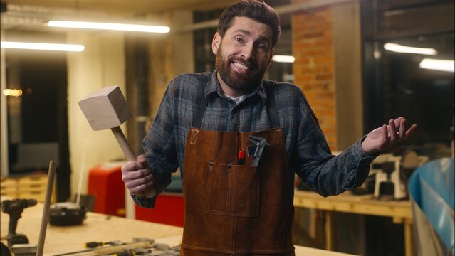 Puzzled Caucasian repairman wood master man builder looking at wooden hammer in workshop uncertain male craftsman hold hardwood tool unsure handyman guy shrug shoulders artist express doubt don't know - Powered by Adobe